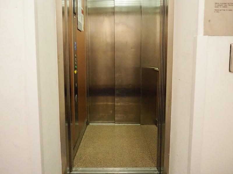 The interior of the lift with metal walls and a lino floor